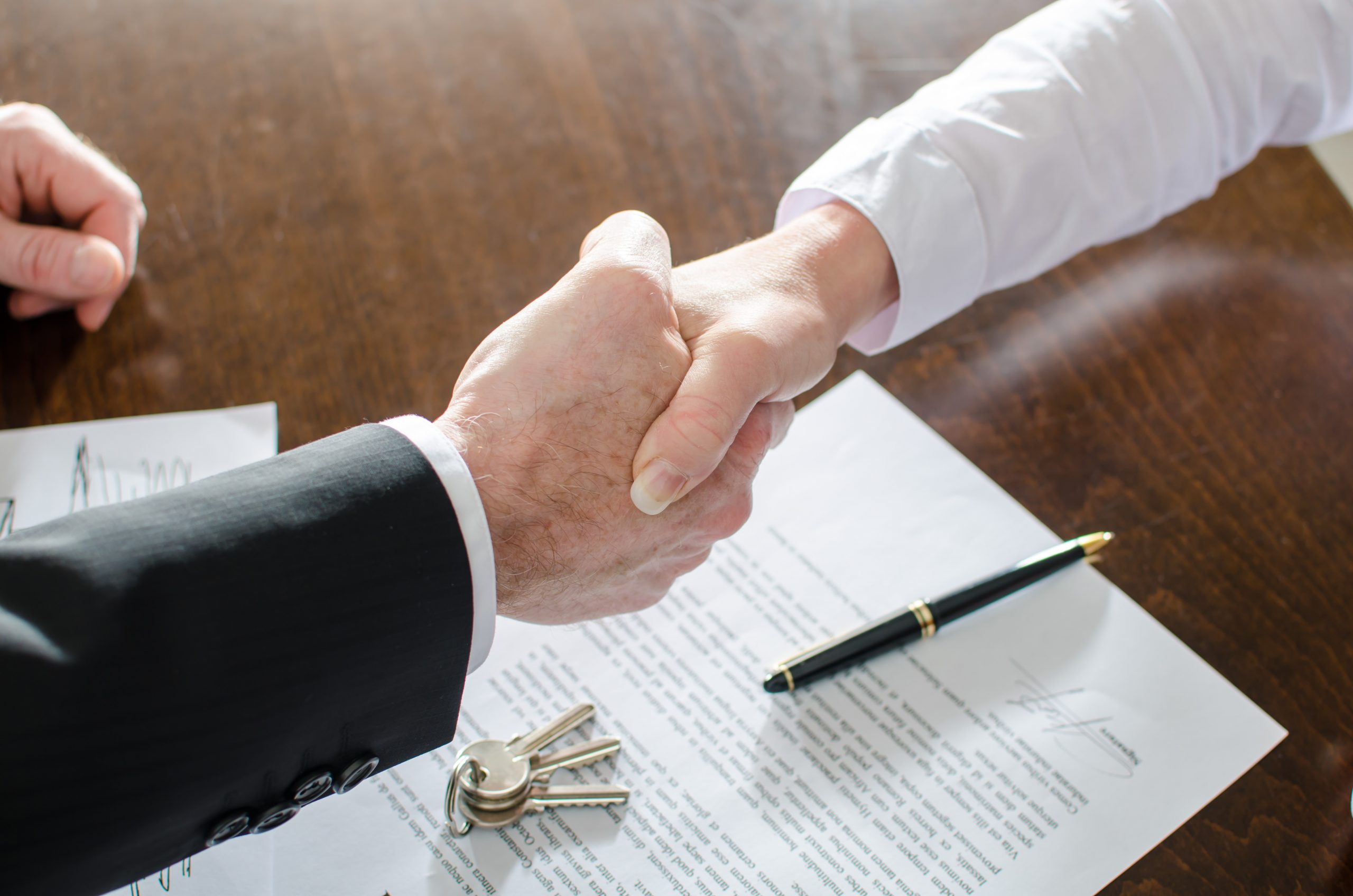 A business owner and a lender reviewing documents at a commercial real estate closing table in a bright conference room