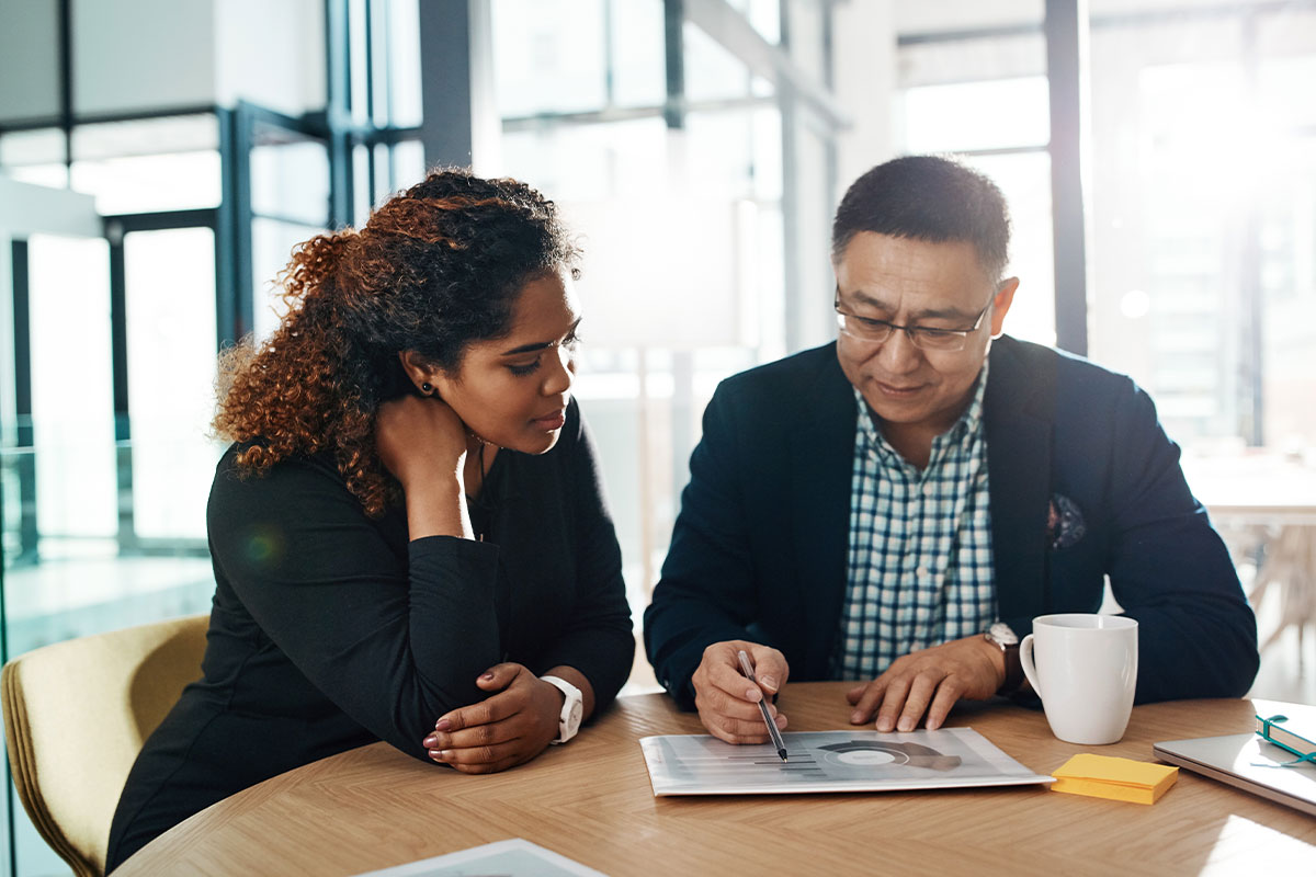 A business owner sitting across from a banker in a modern office, reviewing loan documents on a desk