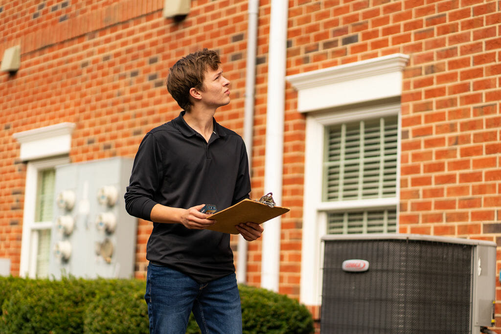 A commercial real estate appraiser standing in a warehouse aisle taking notes on a clipboard during a property inspection