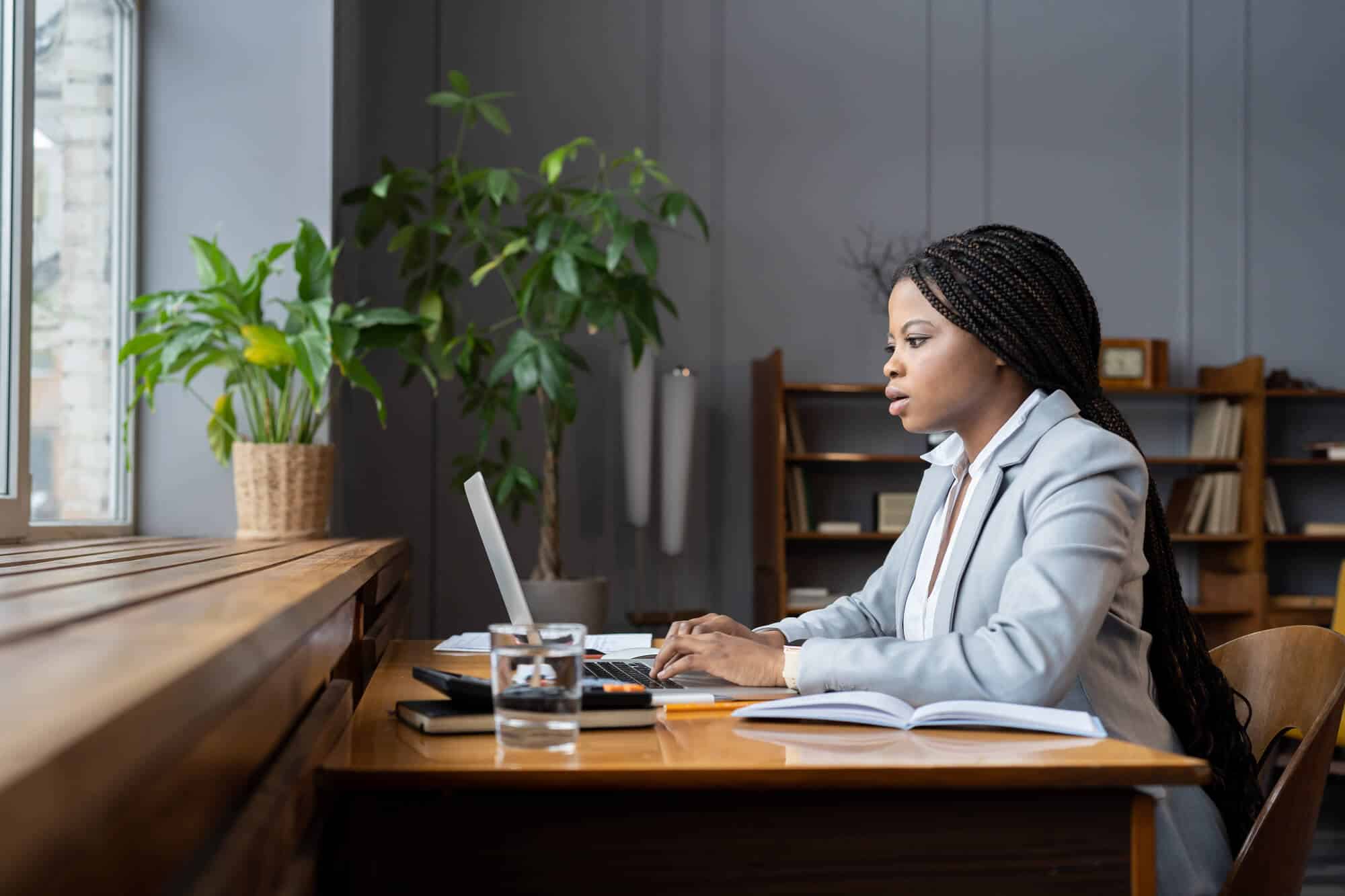 A consultant in a modern office closing a laptop and setting a notebook aside, looking thoughtful and preparing to make a phone call