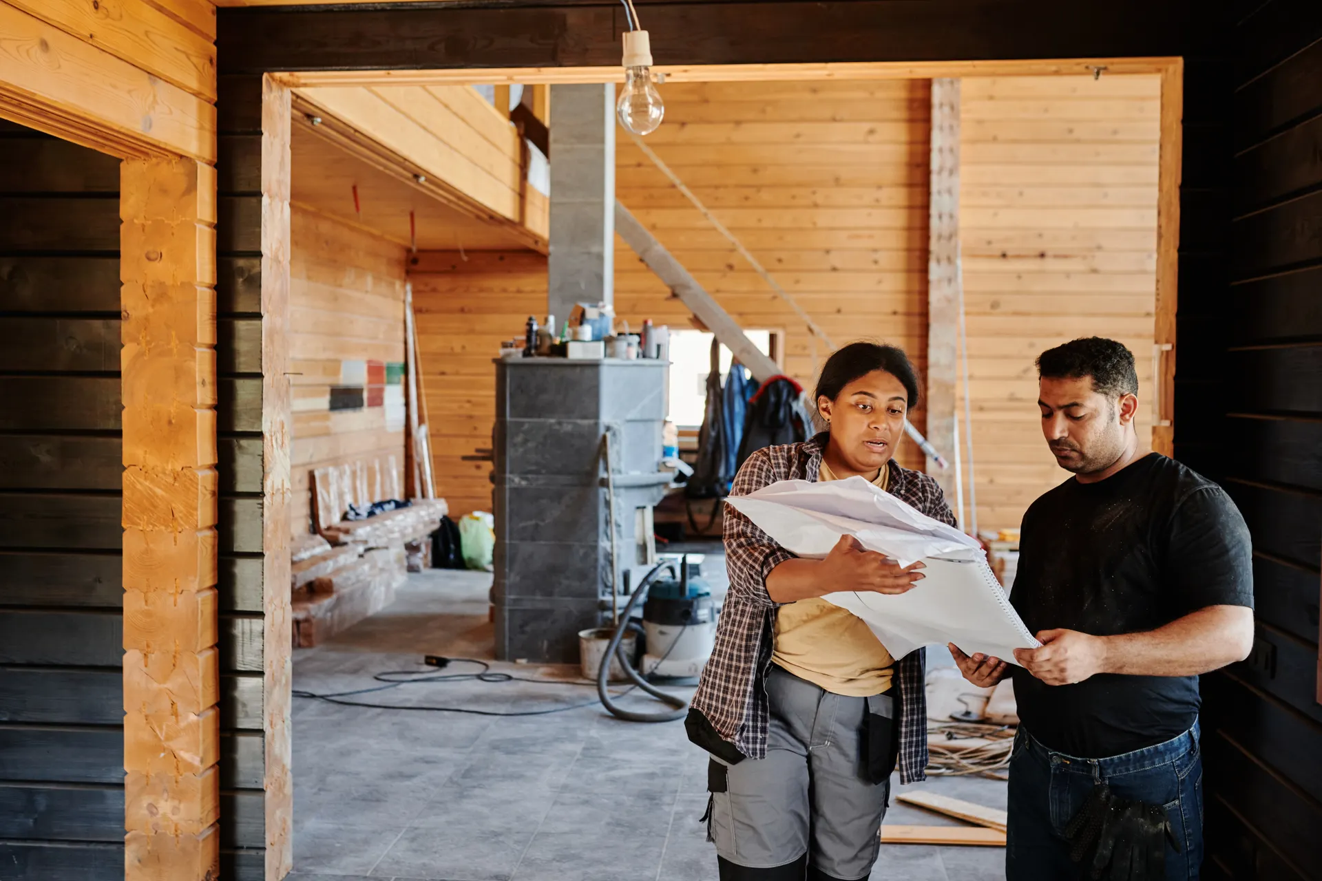 A contractor discussing a kitchen renovation plan with a homeowner inside a partially remodeled kitchen