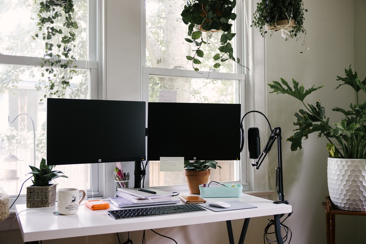 A freelancer working in a tidy home office with a desktop computer, a notebook, and office equipment on the desk.