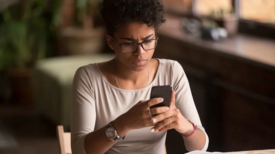 A homeowner holding a phone and reviewing loan documents while calling their bank to ask about HELOC repayment terms