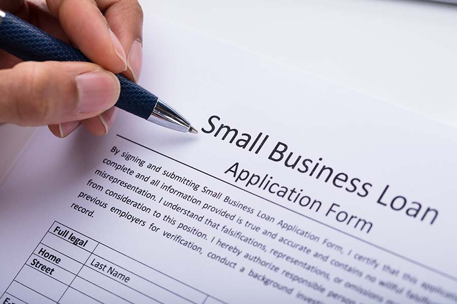 A small business owner and a banker seated at a desk, reviewing and signing loan paperwork in a quiet office