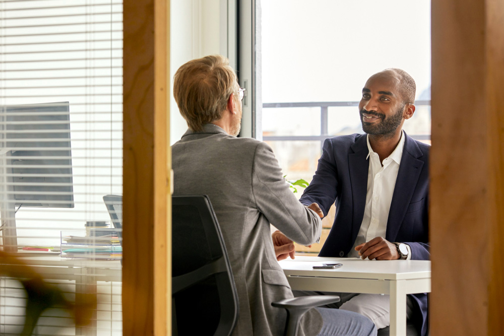 A small business owner sitting across a desk from a banker in a local branch office, reviewing loan documents