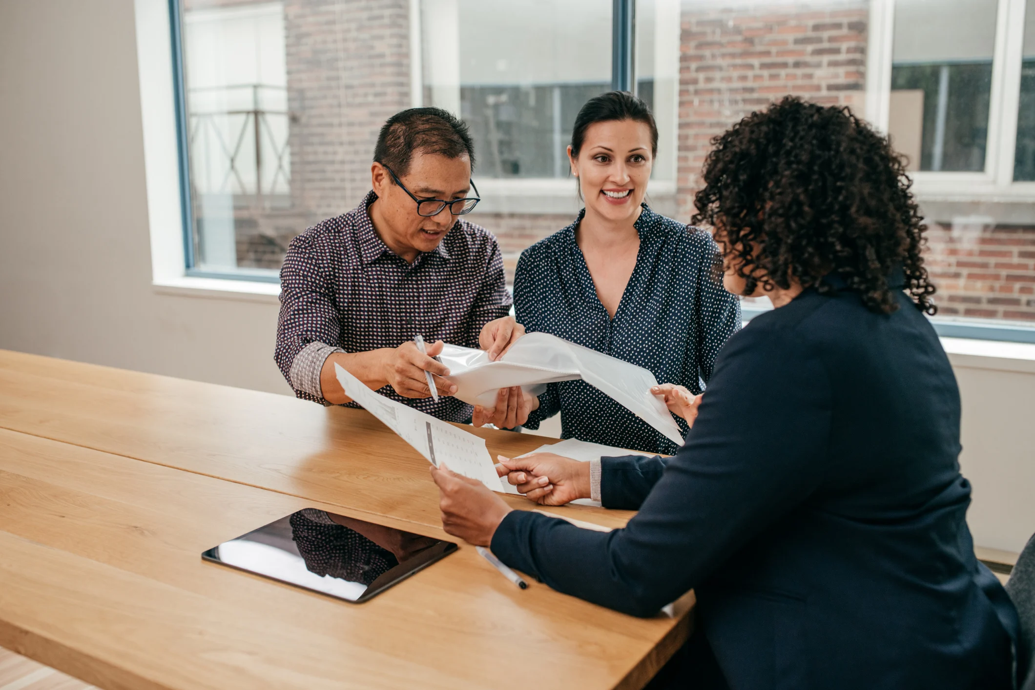 A small business owner sitting across from a bank loan officer in a branch office, both reviewing documents on a table