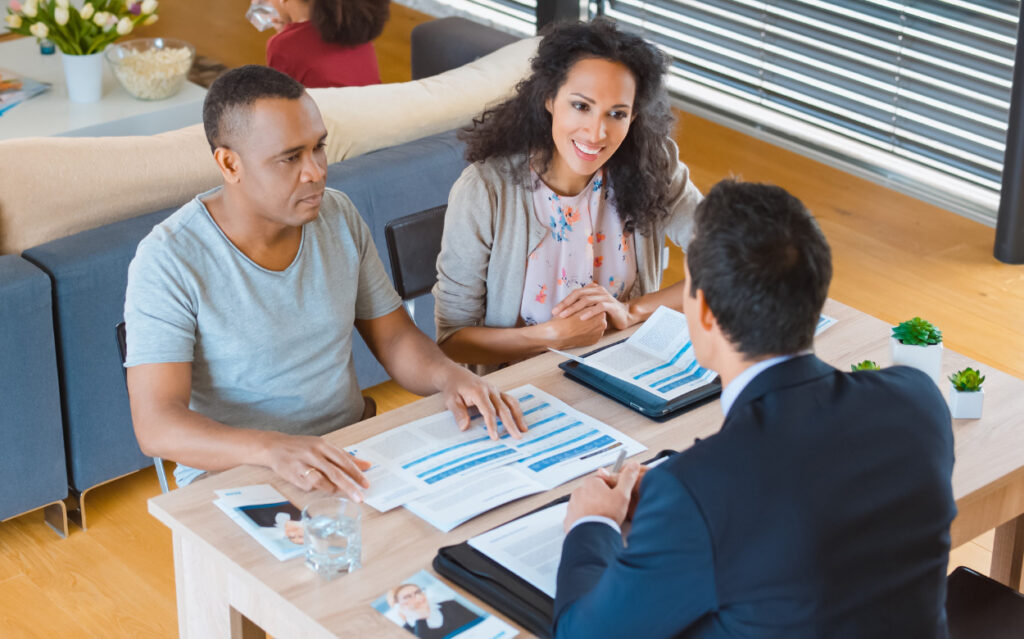 A small business owner sitting across from a banker at a conference table, reviewing printed loan documents in a bright office