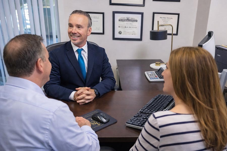 A small business owner sitting across from an accountant at a conference table reviewing paperwork and a laptop in a professional office