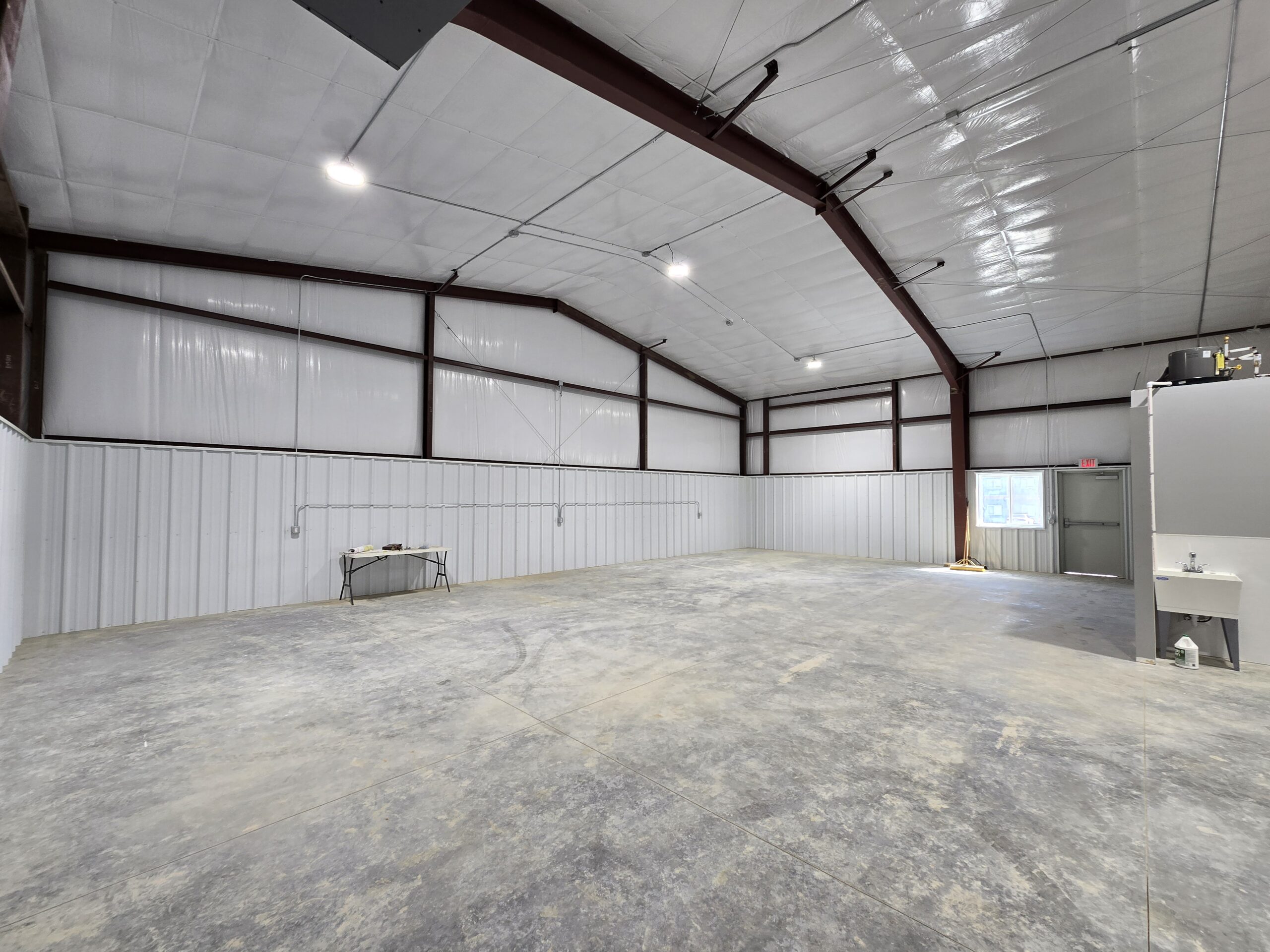 A small business owner standing inside an owner-occupied light industrial warehouse space with shelving and pallets in the background