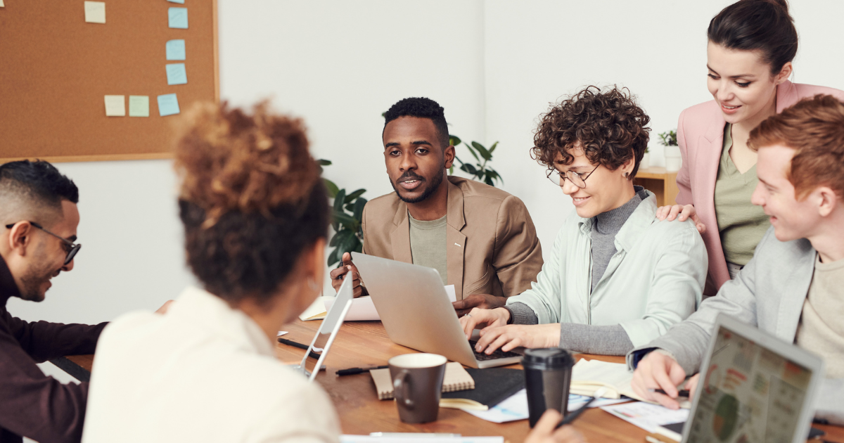 A small team of employees sitting around a conference table during a casual benefits discussion in a modern office