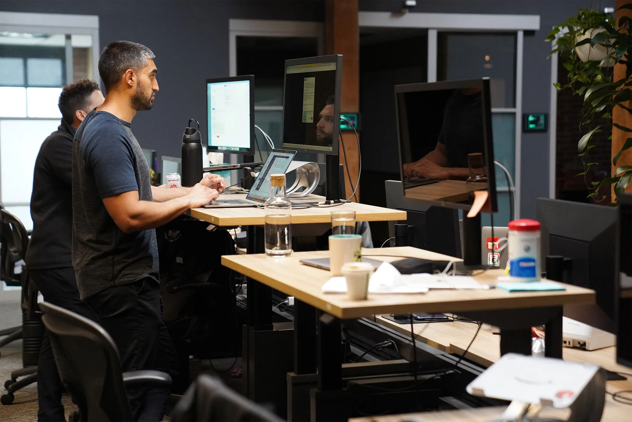 A startup founder sitting at a desk with a laptop, bank statements, and a calculator