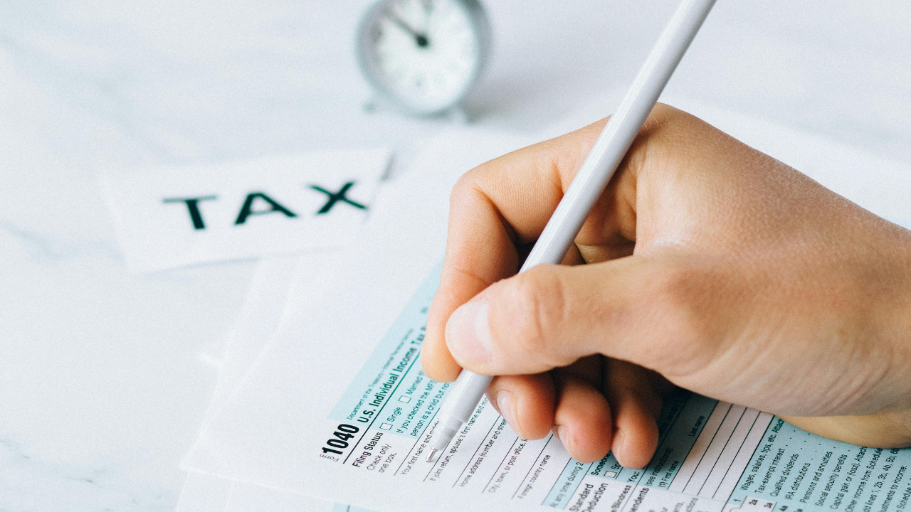 A taxpayer reviews a printed federal tax return at a desk with a calculator and a pen nearby.