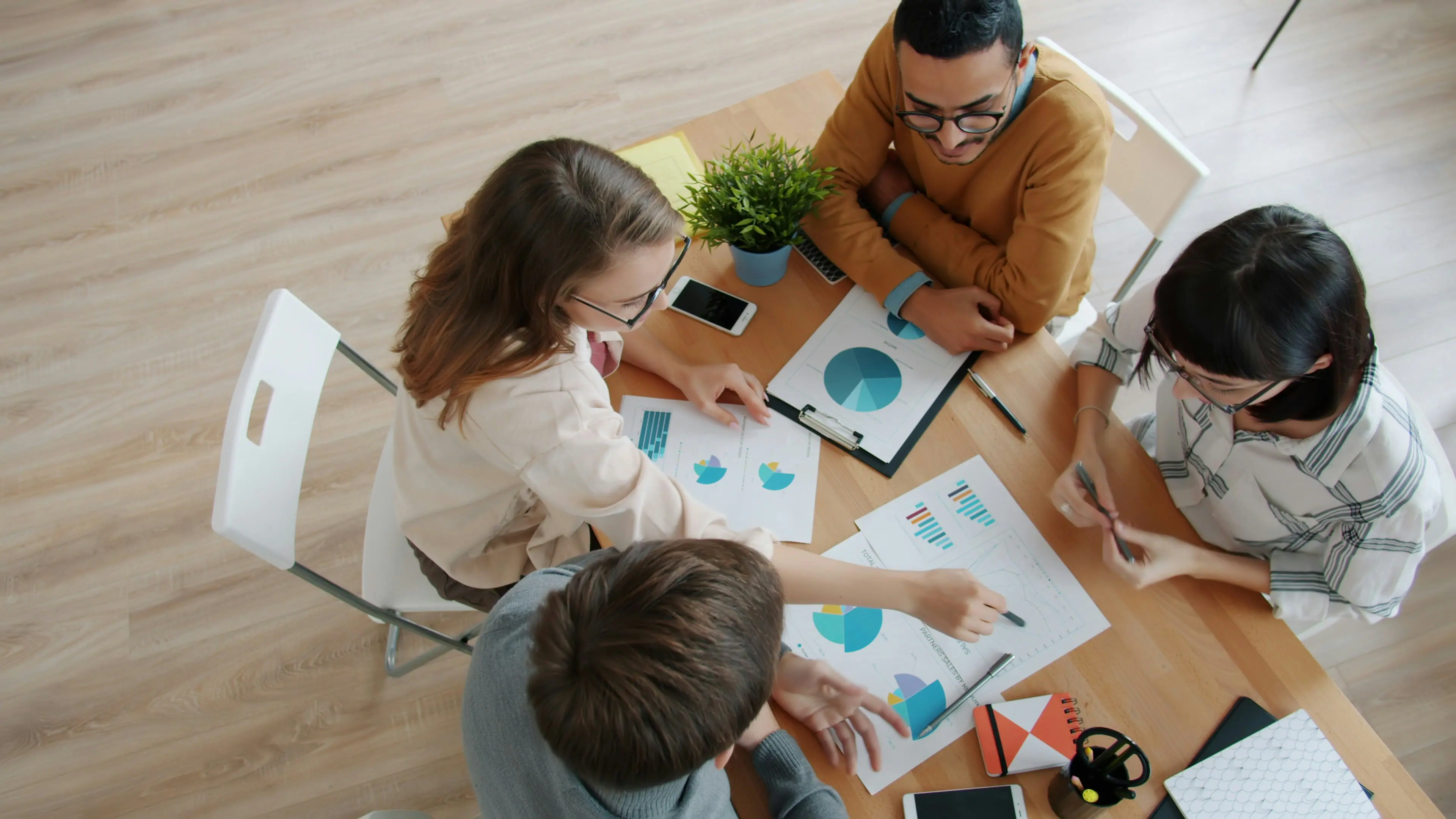 Two small business partners seated at a conference table, reviewing financial documents and a laptop together in a modern office
